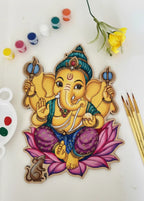 Lord Ganesha DIY art kit contents flat lay - pre-drawn board with Ganesha on pink lotus, acrylic paints and brushes on white background - Arttykase