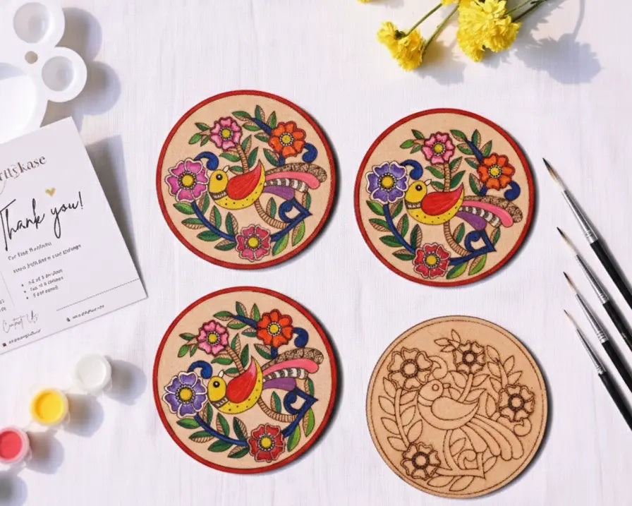 Four finished hand-painted Madhubani bird mandala coasters with colorful Indian folk art bird and floral designs displayed on a white surface
